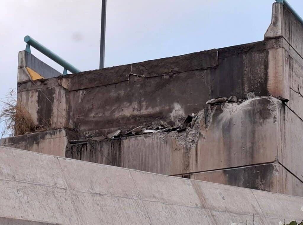 Daños y colapso parcial en el extremo de un puente a desnivel de concreto, con grietas y desprendimiento del tablero sobre el estribo